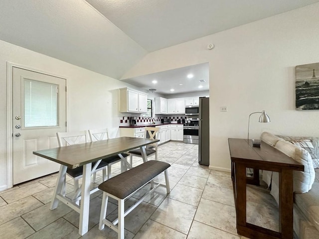 tiled dining room featuring lofted ceiling