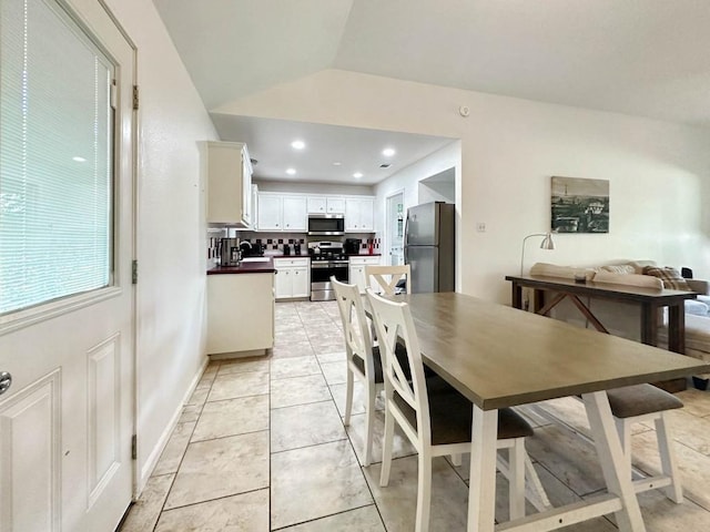 dining space with vaulted ceiling, sink, and light tile patterned flooring