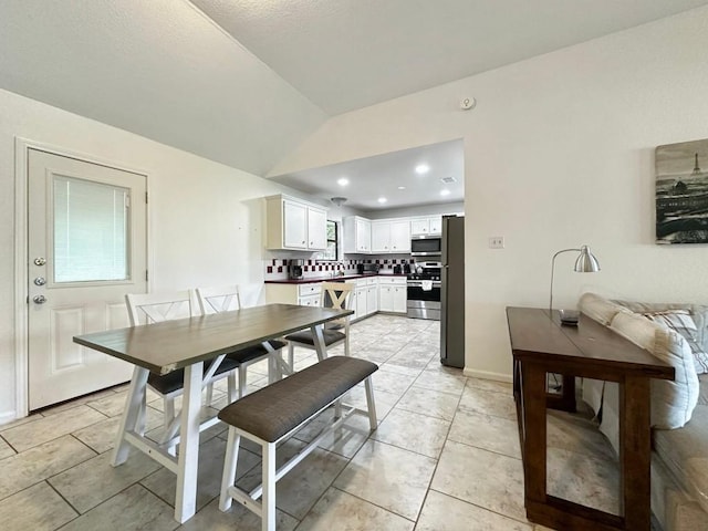 dining area with light tile patterned floors and vaulted ceiling