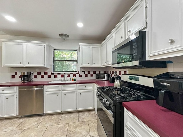 kitchen with sink, decorative backsplash, stainless steel appliances, and white cabinets