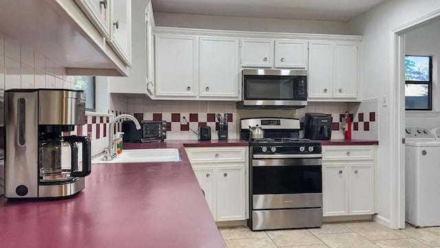 kitchen with appliances with stainless steel finishes, separate washer and dryer, sink, and white cabinets