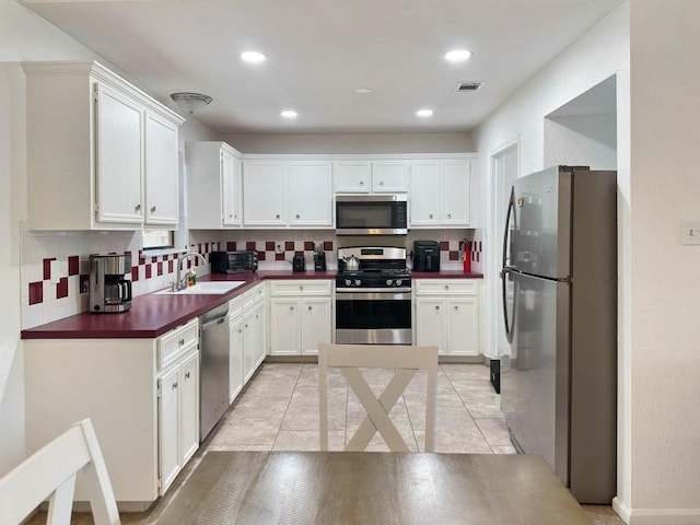 kitchen with stainless steel appliances, sink, white cabinets, and backsplash