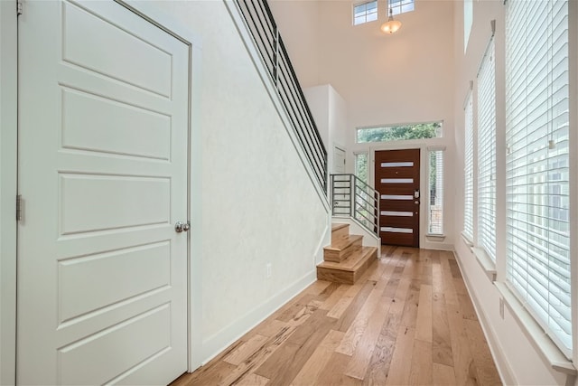 entrance foyer featuring a towering ceiling and light wood-type flooring