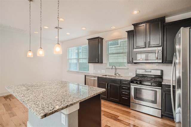 kitchen with sink, hanging light fixtures, a center island, light hardwood / wood-style floors, and stainless steel appliances