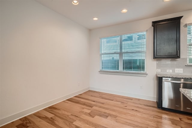 kitchen featuring light stone counters, stainless steel dishwasher, light wood-type flooring, and backsplash