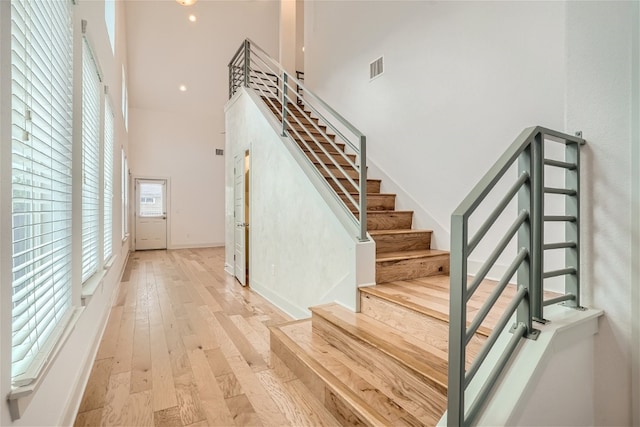 staircase with hardwood / wood-style flooring and a towering ceiling