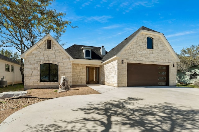 french country style house featuring a garage, driveway, a chimney, and roof with shingles