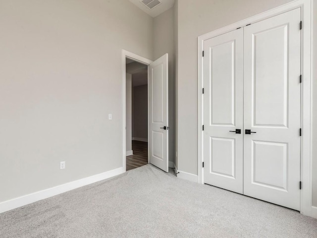 unfurnished bedroom with light colored carpet and a closet