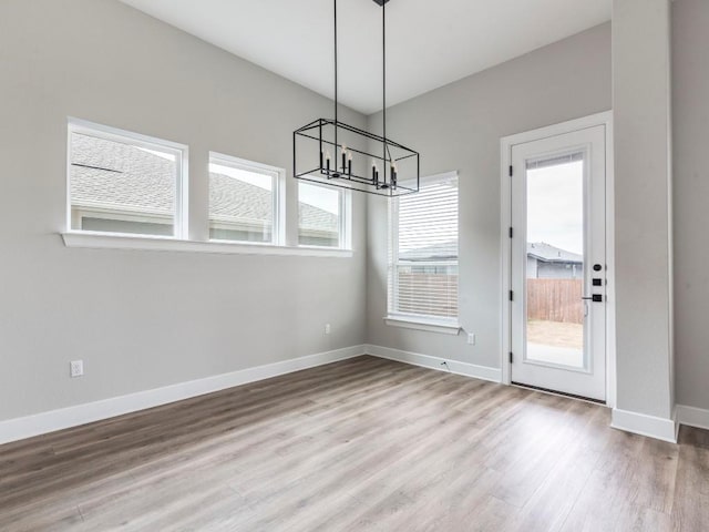 unfurnished dining area featuring hardwood / wood-style floors and a notable chandelier