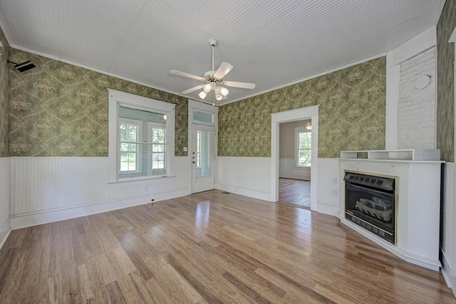 unfurnished living room featuring ceiling fan, ornamental molding, a healthy amount of sunlight, and hardwood / wood-style floors