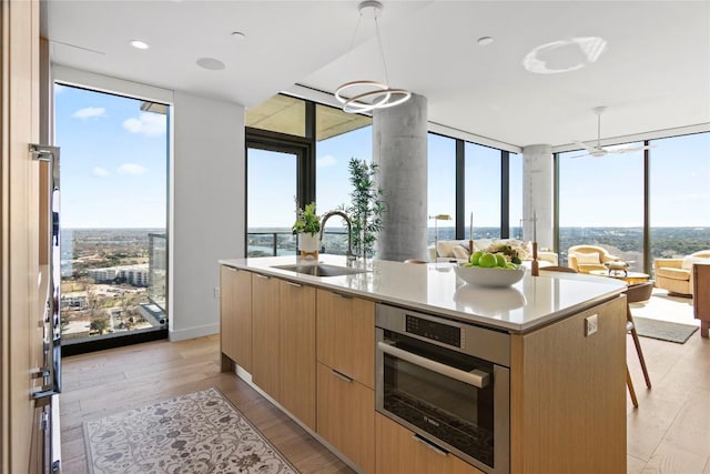 44 E Ave Unit 2310, Austin, TX 78701 - kitchen with a sink, expansive windows, modern cabinets, healthy amount of natural light, and light brown cabinetry