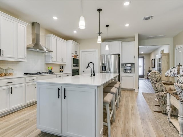 115 Lafayette St, Georgetown, TX 78633 - kitchen with wall chimney exhaust hood, appliances with stainless steel finishes, light wood-style floors, white cabinetry, and recessed lighting