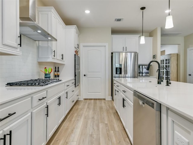 115 Lafayette St, Georgetown, TX 78633 - kitchen featuring stainless steel appliances, wall chimney exhaust hood, a sink, light countertops, and white cabinetry