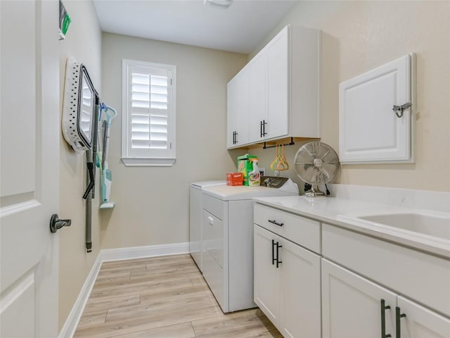 laundry area featuring light hardwood / wood-style floors, cabinets, and washing machine and clothes dryer