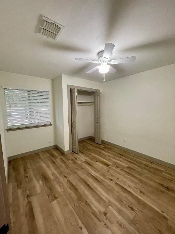 unfurnished bedroom featuring ceiling fan, light hardwood / wood-style floors, and a closet