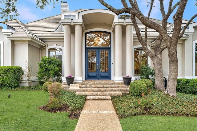 property entrance with a lawn and french doors