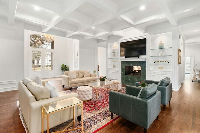 living room featuring hardwood / wood-style floors, built in features, coffered ceiling, a high end fireplace, and beam ceiling