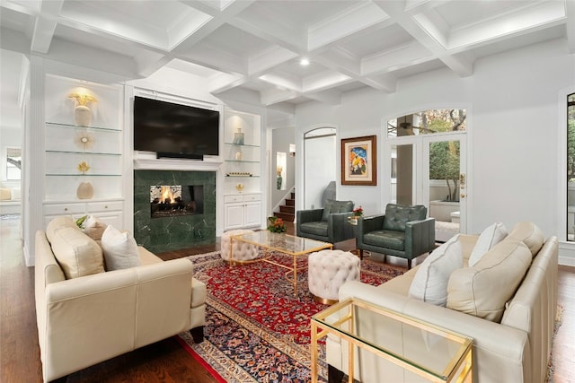 living room featuring beamed ceiling, wood-type flooring, coffered ceiling, and built in shelves