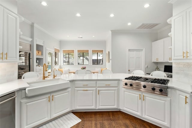 kitchen with sink, white cabinets, kitchen peninsula, stainless steel appliances, and crown molding