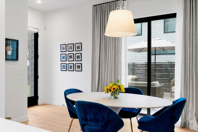 dining space with baseboards, wood finished floors, and recessed lighting