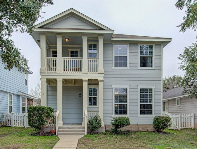 view of front of property with a porch, a balcony, and a front lawn