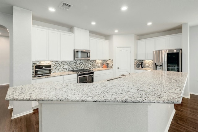 kitchen with stainless steel appliances, a large island, and white cabinets