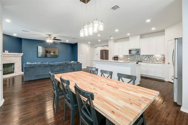 1228 Brenham Ln, Leander, TX 78641 - dining area with a ceiling fan, dark wood-style flooring, a stone fireplace, recessed lighting, and a chandelier