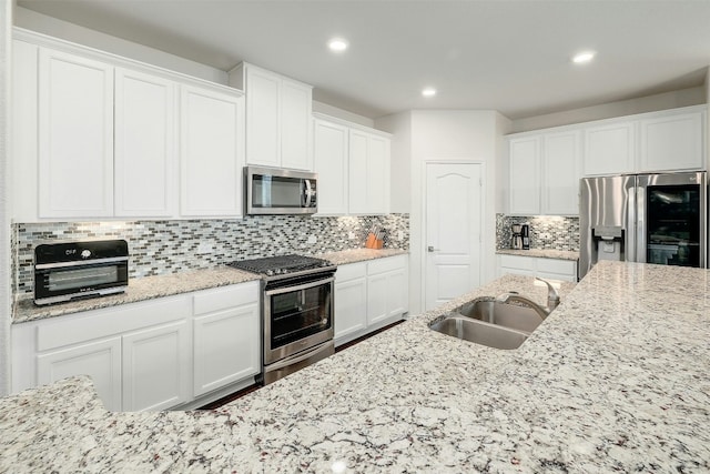 1228 Brenham Ln, Leander, TX 78641 - kitchen featuring appliances with stainless steel finishes, a sink, white cabinetry, recessed lighting, and tasteful backsplash