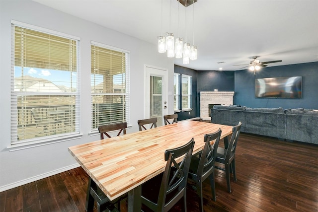 1228 Brenham Ln, Leander, TX 78641 - dining space with dark wood-type flooring, a fireplace, a ceiling fan, and baseboards