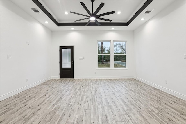 unfurnished room featuring a raised ceiling, ceiling fan, and light wood-type flooring