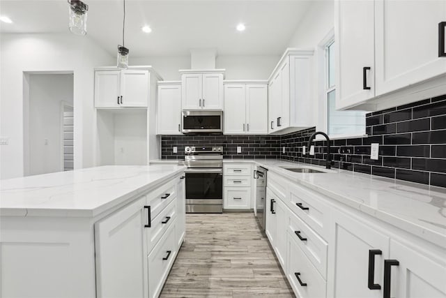 kitchen with appliances with stainless steel finishes, decorative light fixtures, sink, white cabinets, and light stone counters