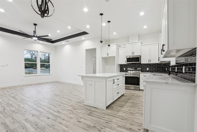 kitchen featuring sink, a center island, hanging light fixtures, appliances with stainless steel finishes, and white cabinets