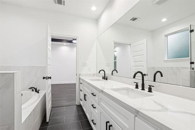 bathroom with tiled tub, vanity, a wealth of natural light, and tile patterned floors