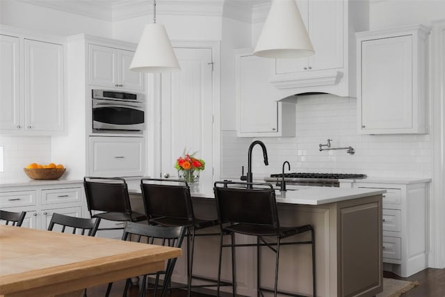 kitchen featuring white cabinetry, appliances with stainless steel finishes, a kitchen breakfast bar, and a kitchen island with sink