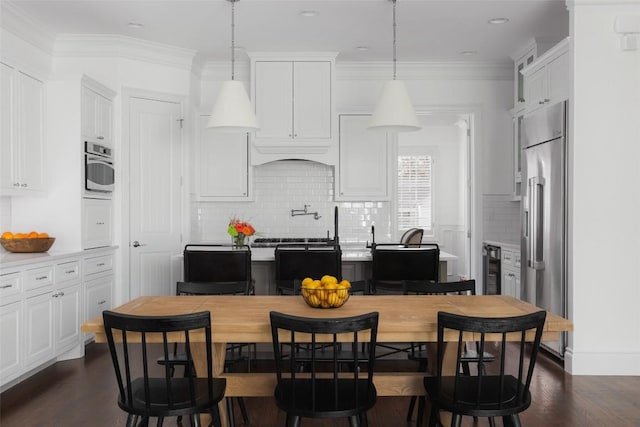 kitchen featuring ornamental molding, dark hardwood / wood-style flooring, pendant lighting, stainless steel appliances, and white cabinets