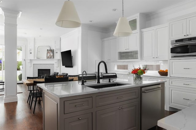 kitchen featuring appliances with stainless steel finishes, sink, white cabinets, light stone counters, and crown molding