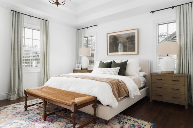 bedroom with dark wood-type flooring and a raised ceiling