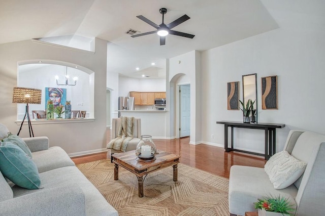 living room with lofted ceiling, ceiling fan with notable chandelier, and light hardwood / wood-style floors