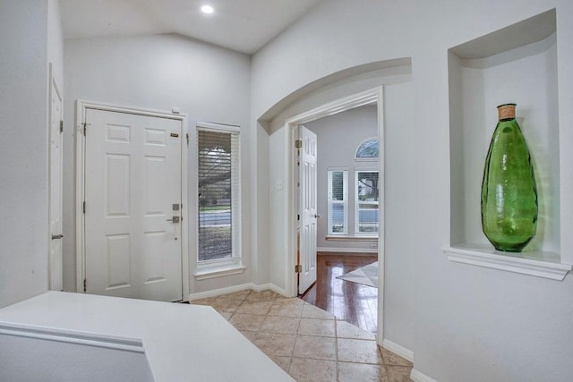 foyer featuring plenty of natural light, light tile patterned floors, and lofted ceiling