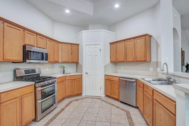 kitchen featuring sink, a towering ceiling, and appliances with stainless steel finishes