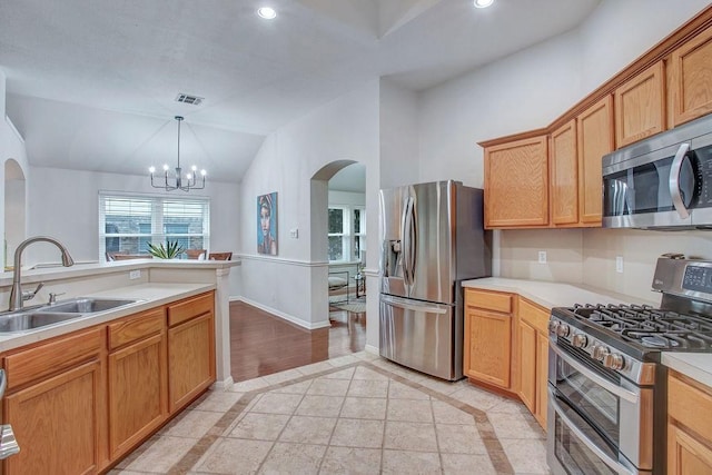 kitchen with sink, appliances with stainless steel finishes, decorative light fixtures, vaulted ceiling, and a chandelier