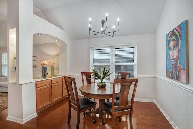 dining room with lofted ceiling, dark hardwood / wood-style floors, and an inviting chandelier