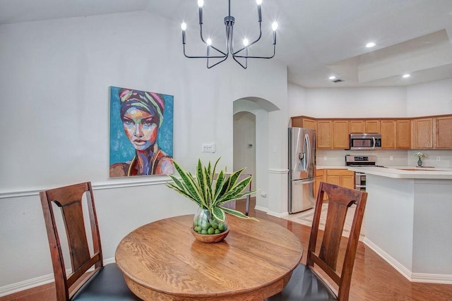 dining area featuring a notable chandelier, a towering ceiling, and light wood-type flooring