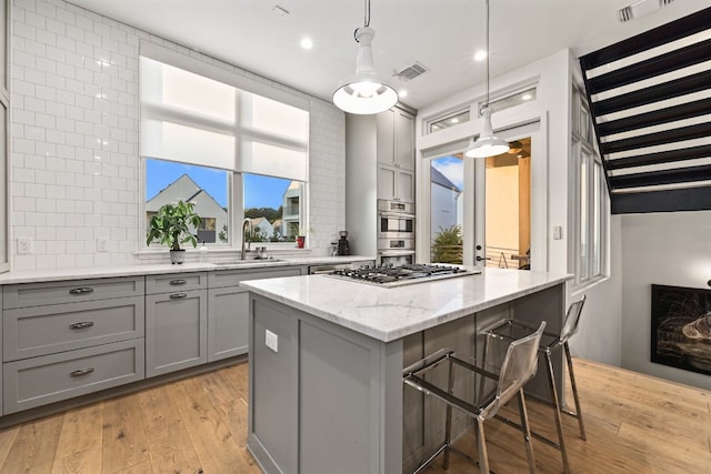 kitchen with pendant lighting, sink, a kitchen bar, a center island, and light stone countertops