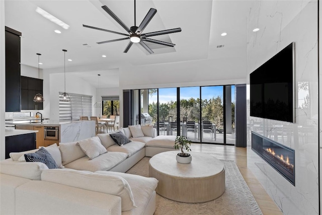 living room featuring ceiling fan, a premium fireplace, and sink