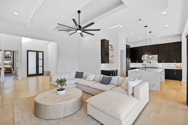 living room with ceiling fan with notable chandelier, light hardwood / wood-style floors, and french doors