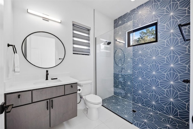 bathroom with tiled shower, vanity, toilet, and tile patterned floors