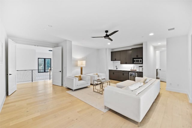 living room featuring wine cooler, light hardwood / wood-style flooring, and ceiling fan