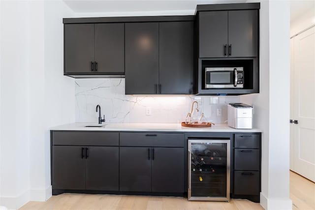 bar with wine cooler, sink, backsplash, and light hardwood / wood-style floors