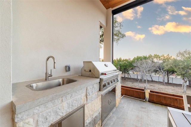 patio terrace at dusk featuring a grill, an outdoor kitchen, and sink